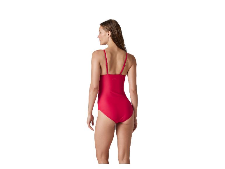 Femme en maillot de bain une pièce rouge, vue de dos, regardant par-dessus son épaule.