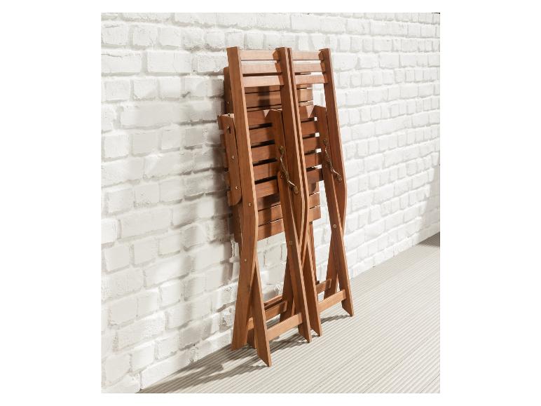 Deux chaises pliantes en bois contre un mur de briques blanches