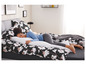 Une femme dort sur un lit avec un oreiller blanc et une couette noire à imprimé floral.