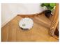 Aspirateur robot blanc sur un parquet en bois près d'un escalier.