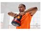Un homme en t-shirt orange tient un kettlebell de 10 kg.