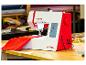 Machine à coudre rouge et blanche avec tissu sur une table en bois dans un atelier