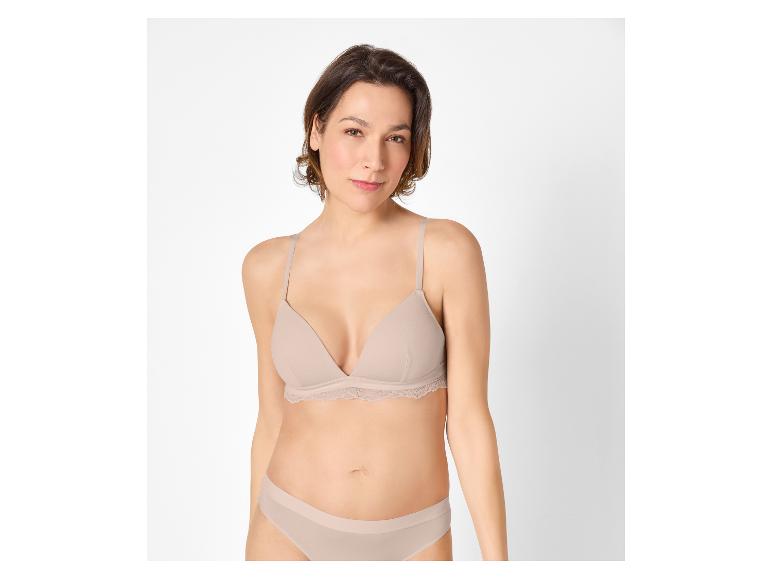 Femme en soutien-gorge et culotte beiges, regardant droit devant.