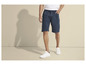 Un homme portant un short bleu avec un cordon de serrage et des baskets blanches.