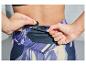 Une femme rangeant une clé dans la poche de son pantalon de sport.