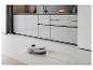 Un aspirateur robot nettoie un sol en carrelage blanc dans une cuisine moderne.
