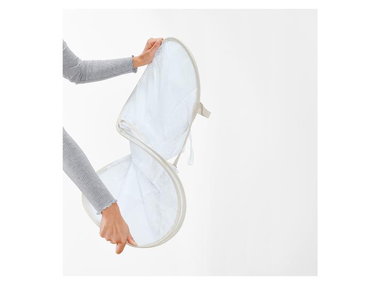 Une personne tenant un panier à linge pliable en filet.