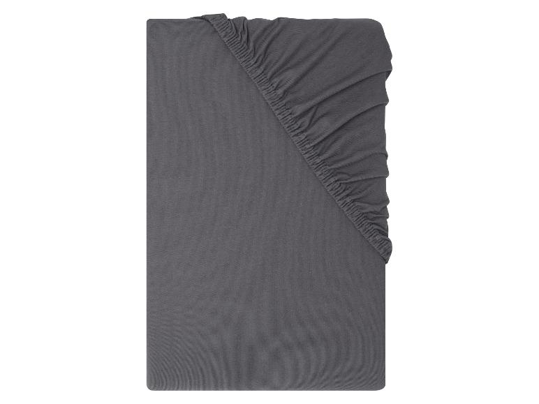 Drap-housse gris foncé avec élastique dans le coin supérieur droit.