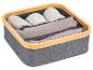 Une boîte de rangement en tissu gris avec une bordure en bois, remplie de vêtements pliés.