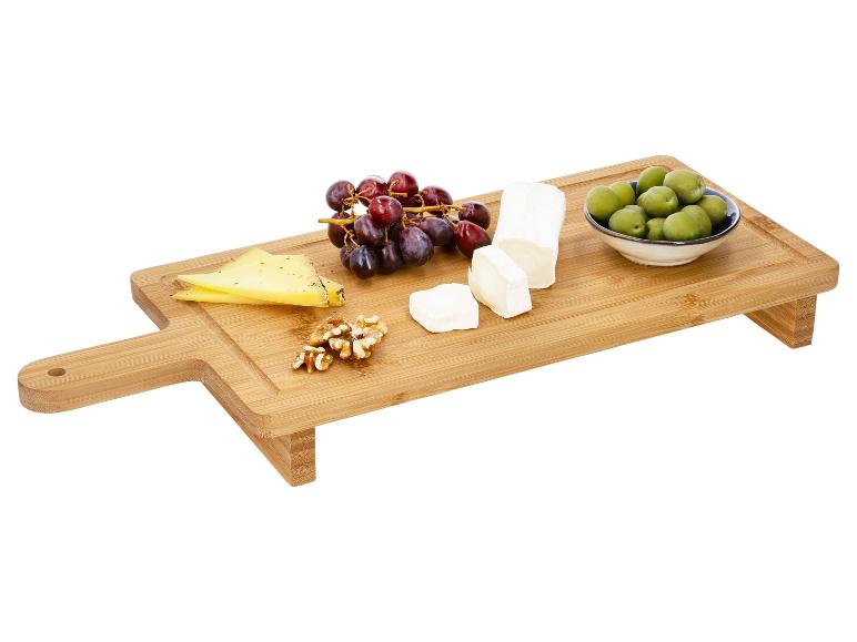 Planche à découper en bois avec fromage, raisins, noix et olives