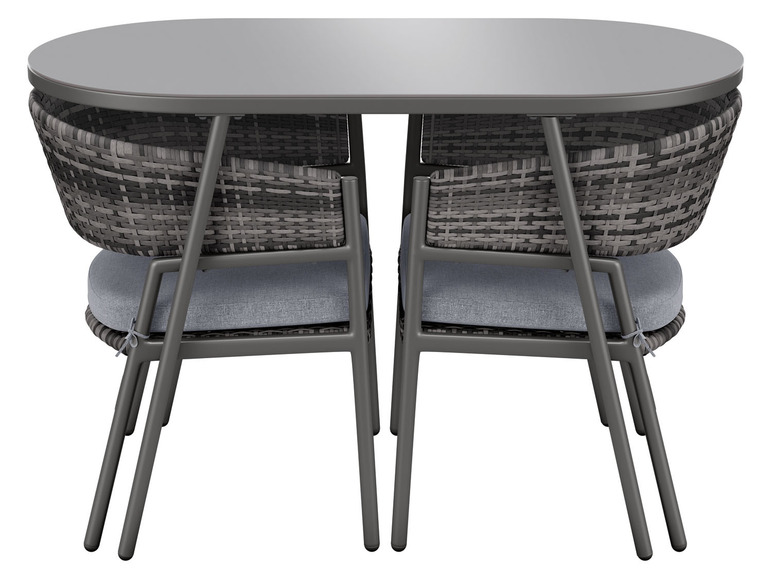 Une table ovale avec deux chaises en osier avec des coussins.