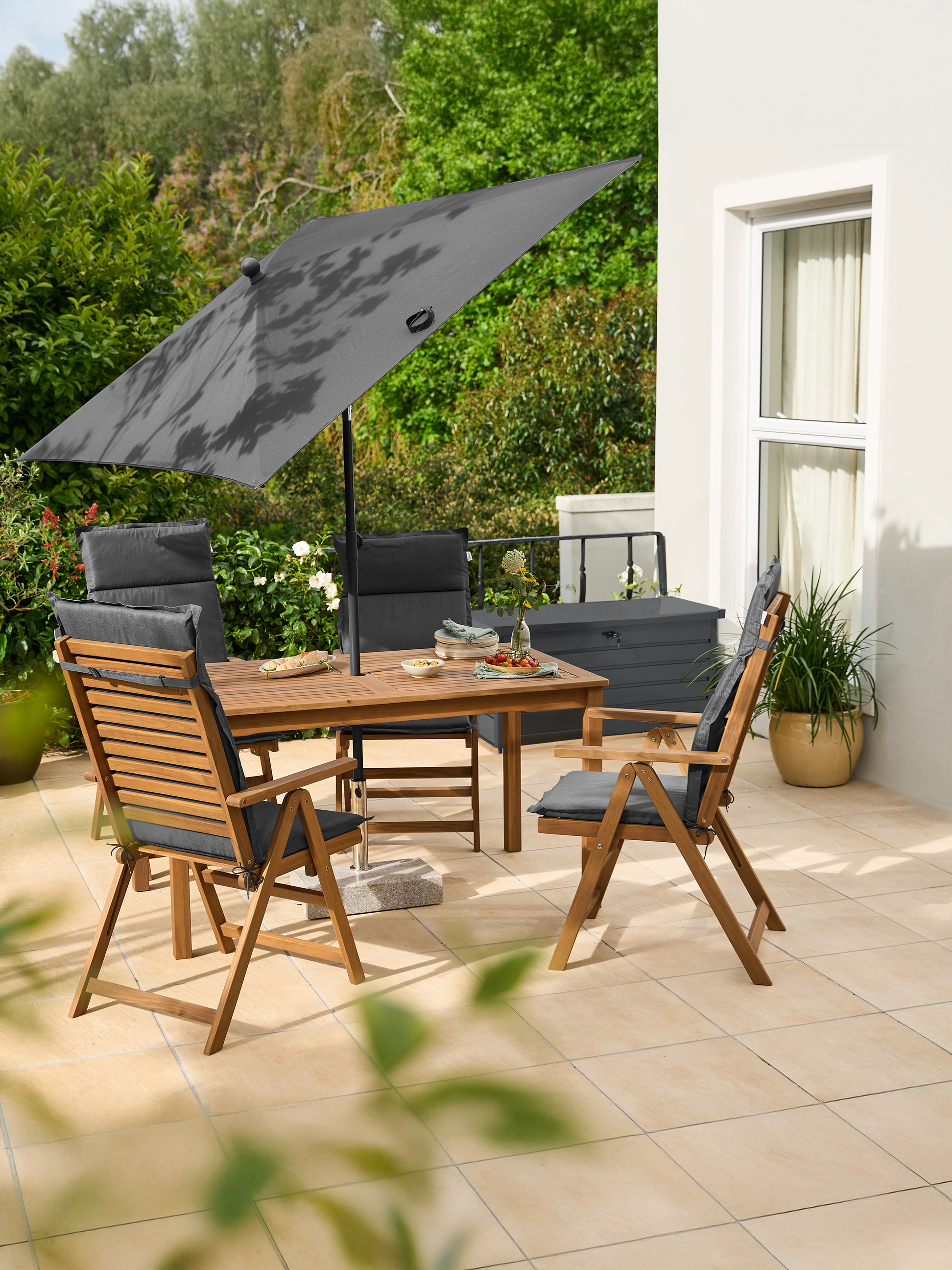 Ensemble de mobilier de jardin en bois avec coussins gris et grand parasol gris sur une terrasse carrelée.