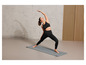 Une femme faisant du yoga sur un tapis gris
