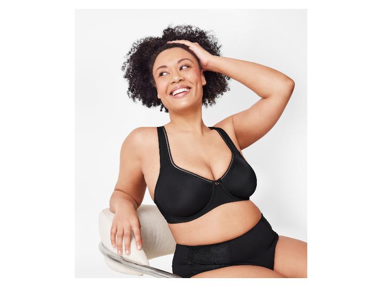 Une femme sourit en portant un soutien-gorge noir Elomi Cate à armatures et des sous-vêtements taille haute.