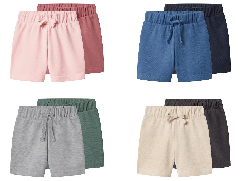 Quatre paires de shorts pour enfants en rose, bleu, gris et beige, chacun avec une couleur complémentaire plus foncée.
