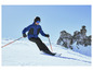 Un skieur en tenue de ski bleue descend une pente enneigée.