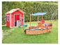Aire de jeux extérieure pour enfants avec une cabane rouge et un bac à sable en forme de bateau