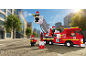 Camion de pompiers en jouet avec des figurines de pompiers dans une rue.