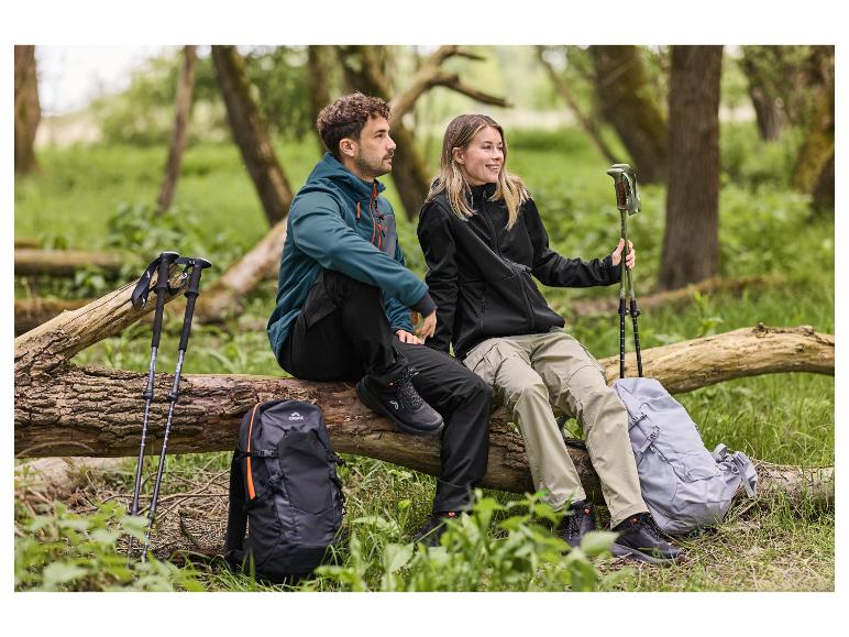 Deux randonneurs assis sur un tronc d'arbre, avec des chaussures de randonnée, des vestes et des sacs à dos.