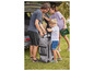 Une famille charge une grande valise et une powerbank Parkside dans la voiture.
