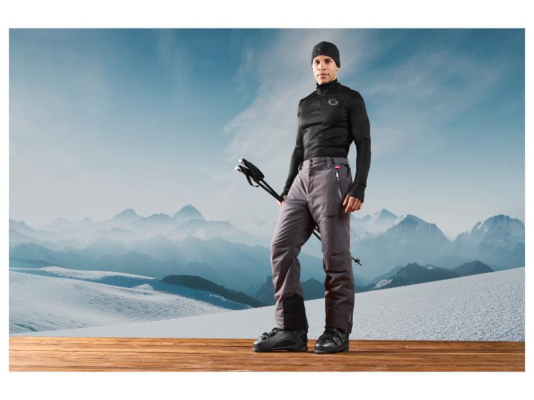 Homme en tenue de ski avec des bâtons devant un paysage montagneux