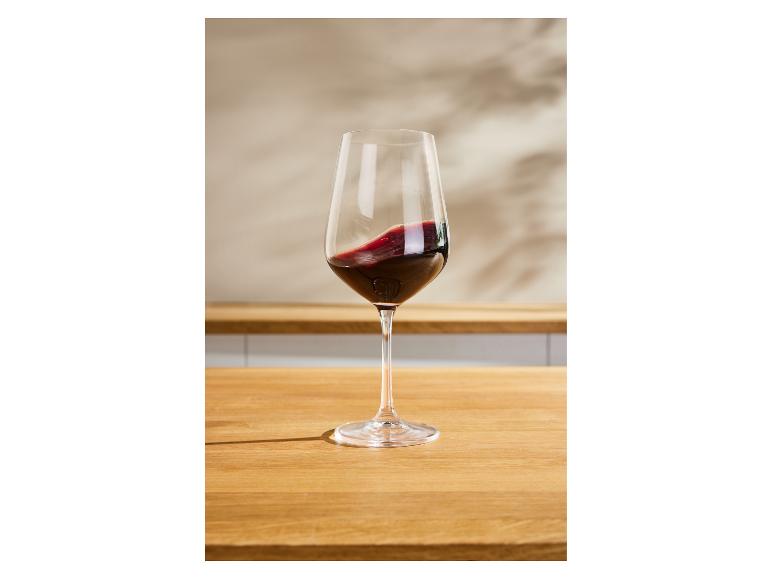 Verre de vin rouge sur une table en bois, avec un arrière-plan flou.