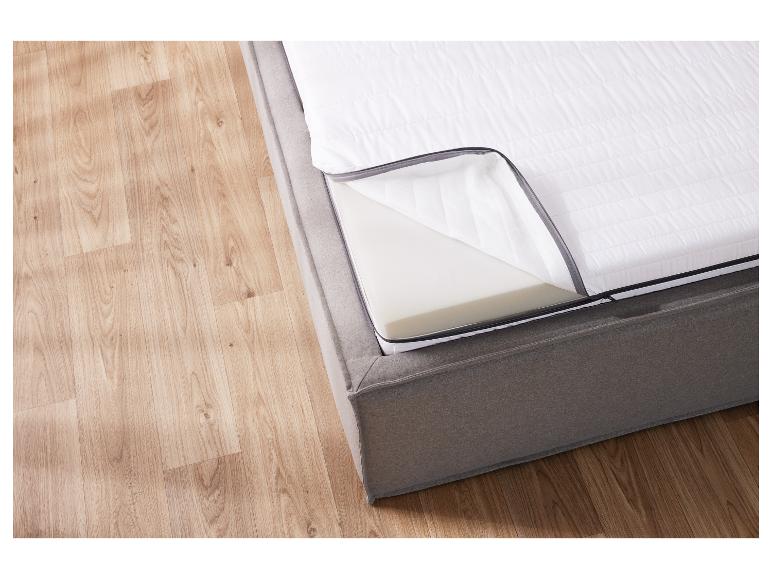 Un lit gris avec matelas et oreiller