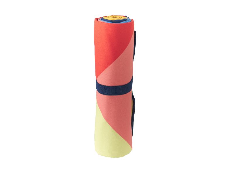 Serviette de plage roulée avec motifs géométriques rouges, roses et jaunes, avec une sangle bleu marine.