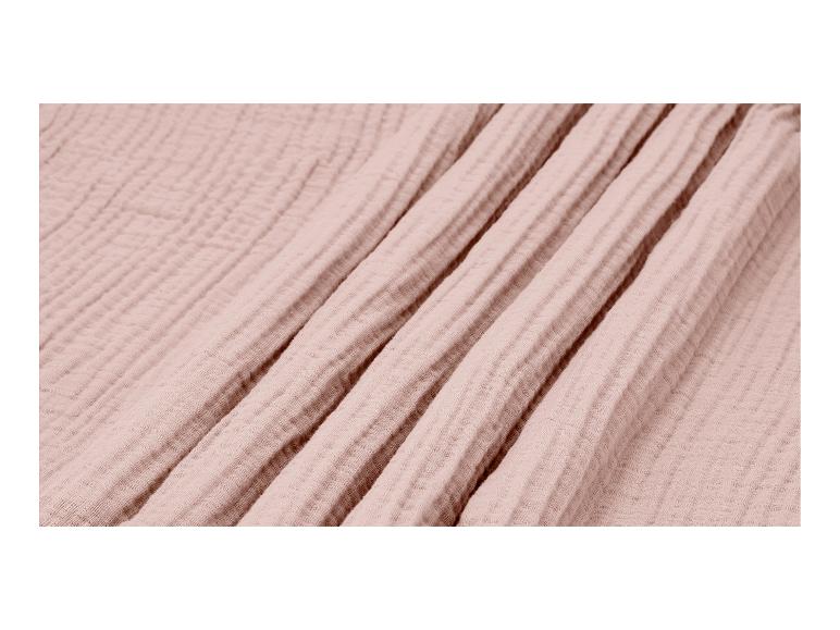 Gros plan d'un tissu en mousseline doux, rose clair, avec des plis et des froissements subtils