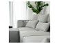Canapé modulaire gris avec coussins et une plante verte dans un vase argenté.