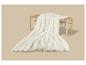 Plaid en fausse fourrure blanche sur un banc en bois sur fond beige.