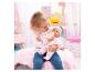 Fille nourrissant une poupée bébé au biberon, assise sur une couverture rose.