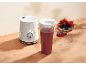 Blender blanc avec un gobelet de smoothie et un bol de baies.
