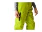 Personne en pantalon de ski vert vif avec une main sur une poche zippée.
