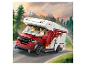 Un camping-car Lego rouge et blanc avec deux figurines au volant, sur une route de montagne.