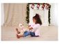 Une enfant joue avec un lapin en peluche devant une cheminée décorée de chaussettes de Noël.