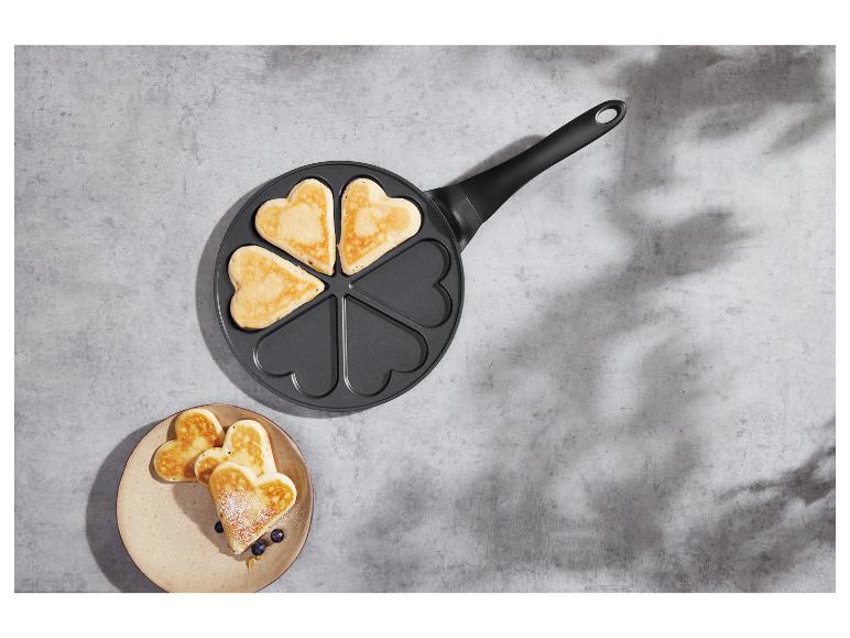 Crêpes en forme de cœur dans une poêle et sur une assiette.