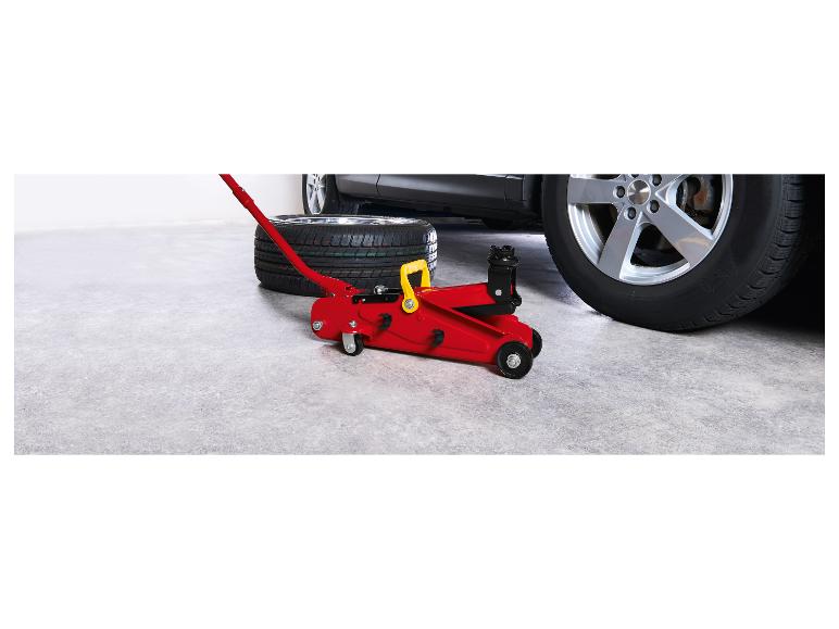 Cric de voiture rouge et pneu à côté d'une voiture dans un garage.