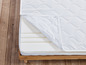 Un matelas blanc avec une housse sur un cadre en bois.