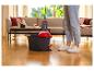 Personne utilisant une serpillière et un seau Vileda pour nettoyer un parquet dans un salon.