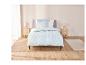 Un lit avec une couette bleu clair à motifs géométriques.