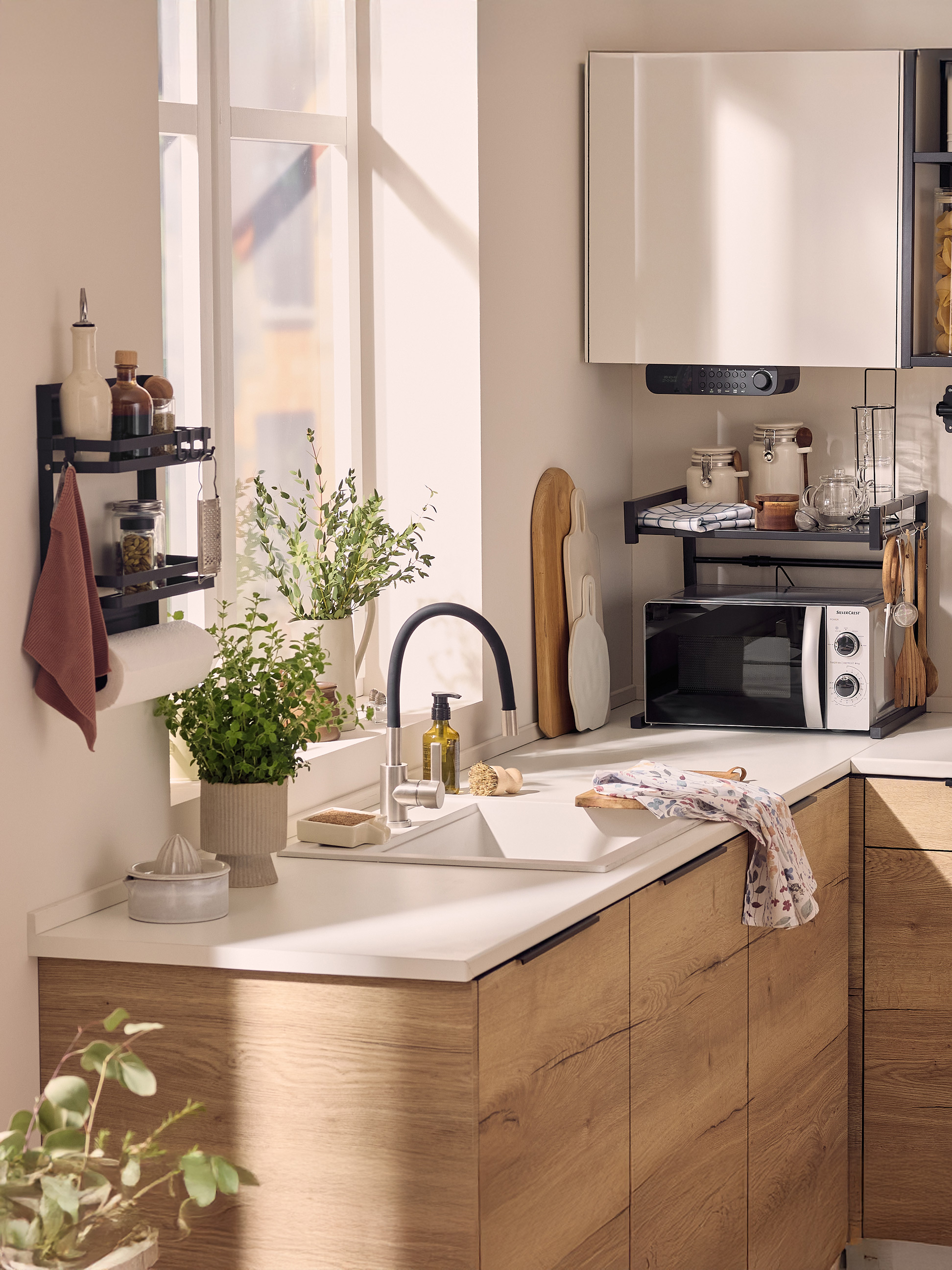 Cuisine moderne avec évier, micro-ondes, étagères murales et plantes vertes.