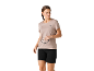 Femme en t-shirt de sport beige et short noir, tenant des lunettes de soleil.