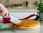 Une main coupant un gâteau avec un couteau.