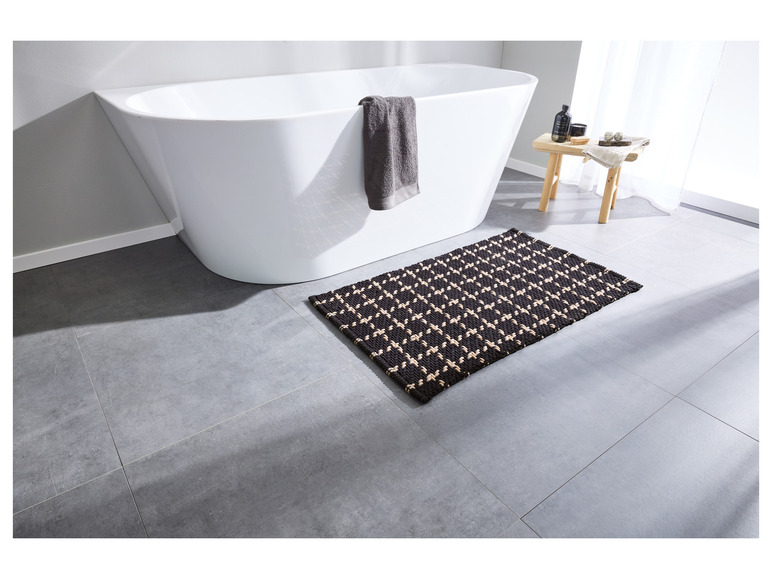 Une baignoire blanche avec un tapis de bain noir dans une salle de bain.