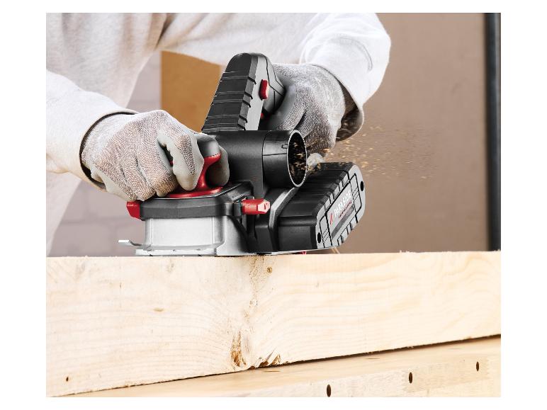 Rabot électrique sans fil en action, avec des copeaux de bois s'envolant d'une planche en bois.