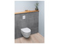 Des toilettes suspendues blanches avec un réservoir encastré et une étagère en bois sur le mur.