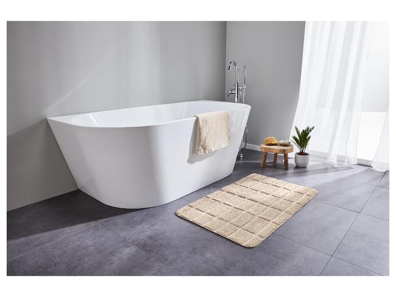 Une baignoire autoportante avec un tapis de bain dans une salle de bain moderne.
