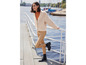 Une femme portant un pull en tricot beige, un pantalon marron et des bottes noires.