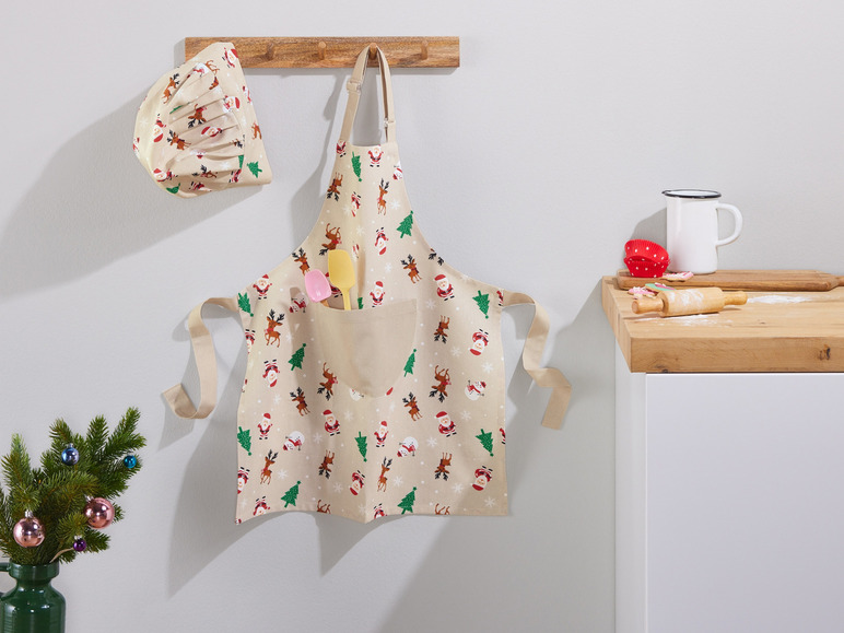Un tablier de Noël avec des rennes et des pères Noël, un chapeau de cuisinier de Noël assorti et des ustensiles de cuisine.